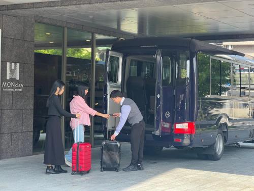 a group of people getting off a bus with luggage at hotel MONday Haneda Airport in Tokyo