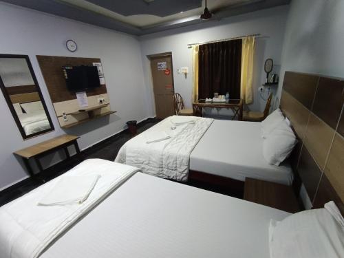 a hotel room with two beds and a tv at Sri Murugan Beach Paradise Hotel in Mahabalipuram
