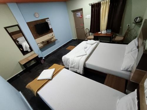 a hotel room with two beds and a tv at Sri Murugan Beach Paradise Hotel in Mahabalipuram
