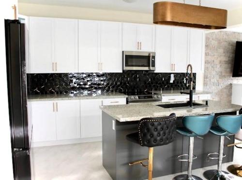 eine Küche mit weißen Schränken und blauen Barhockern in der Unterkunft Luxury, Home Away from Home in Brampton