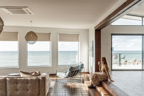 a woman sitting in a living room looking out at the ocean at Novo Luxury Apartment Penguin Accommodation Itas in Penguin