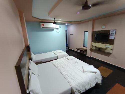 a hospital room with two beds and a flat screen tv at Sri Murugan Beach Paradise Hotel in Mahabalipuram