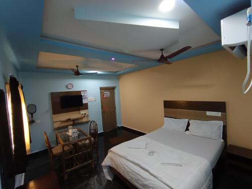 a bedroom with a white bed and a tv at Sri Murugan Beach Paradise Hotel in Mahabalipuram