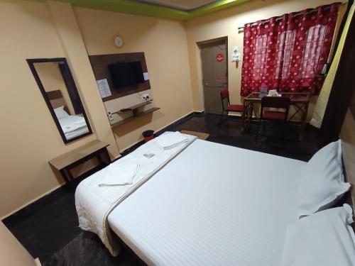 a hotel room with a large bed and a table at Sri Murugan Beach Paradise Hotel in Mahabalipuram