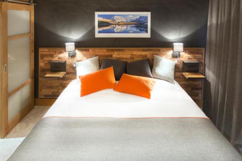 a bedroom with a large bed with orange pillows at Hôtel Saint Charles Val Cenis in Lanslebourg-Mont-Cenis