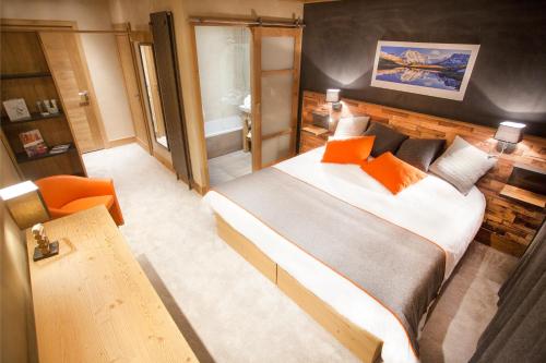 - une chambre avec un grand lit et une chaise orange dans l'établissement Hôtel Saint Charles Val Cenis, à Lanslebourg-Mont-Cenis