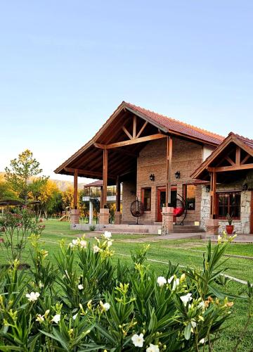 a large building with a green yard with flowers at Ayres del Golf Posada-Restó in Merlo