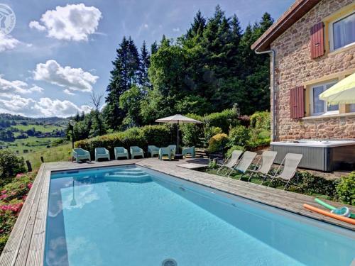 une piscine devant une maison dans l'établissement Maison de campagne avec piscine, spa et jeux extérieurs dans le Haut Beaujolais - FR-1-496-247, à Belmont-de-la-Loire