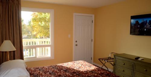 a bedroom with a bed and a window and a dresser at Meaford Inn in Meaford