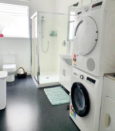 a bathroom with a shower and a washing machine at Ideal location for groups, family, friends or work in Wellington