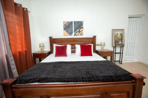 a bedroom with a large bed with red pillows at JesLuv Lodge - West Hills Mall, Accra in New Weija