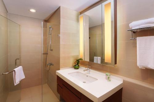a bathroom with a sink and a shower with a mirror at Somerset Kencana Jakarta in Jakarta
