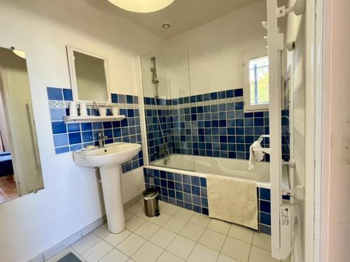 La salle de bains bleue et blanche est pourvue d'un lavabo et d'une baignoire. dans l'établissement Maison spacieuse avec piscine, Wi-Fi et climatisation à La Croix-Valmer - FR-1-226B-204, à La Croix-Valmer