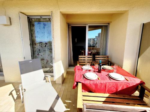 une table avec un chiffon rouge sur un balcon dans l'établissement Canet en Roussillon : T2 front de mer 4 pers, parking, terrasse - FR-1-794-100, à Canet