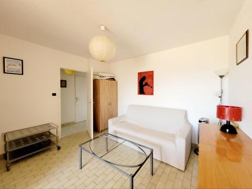 un salon avec un canapé blanc et une table en verre dans l'établissement Canet en Roussillon : T2 front de mer 4 pers, parking, terrasse - FR-1-794-100, à Canet