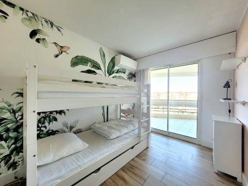 Cette chambre comprend 2 lits superposés et un balcon. dans l'établissement Canet-en-Roussillon - T3 Moderne & Cosy - 6 pers - Clim, Garage - Piscine - FR-1-794-116, à Canet