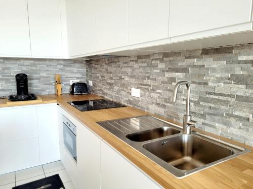 La cuisine est équipée de placards blancs et d'un évier en acier inoxydable. dans l'établissement Canet-en-Roussillon - 6 pers - T3 - Plage directe, PKG, Piscine, Wifi - FR-1-794-128, à Canet