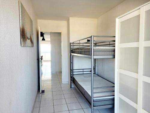 Cette chambre comprend 2 lits superposés et un couloir. dans l'établissement Canet-en-Roussillon - 6 pers - T3 - Plage directe, PKG, Piscine, Wifi - FR-1-794-128, à Canet