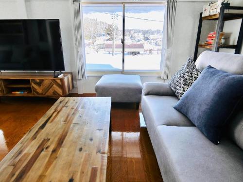 a living room with a couch and a table and a television at Togari Inn Suites in Iiyama
