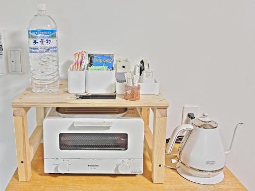 a small table with a microwave and a bottle of water at GUESTHOUSE & SAUNA 杜（mori） in Kushimoto