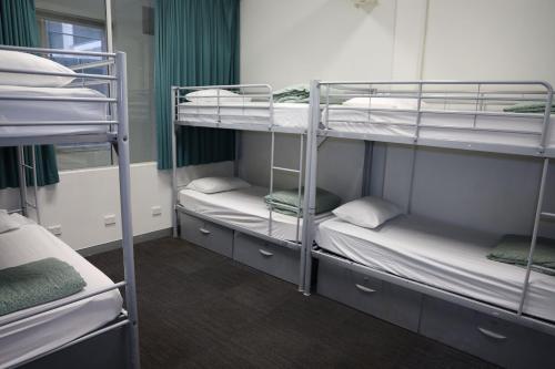 a room with three bunk beds in a room at Nomads Sydney in Sydney
