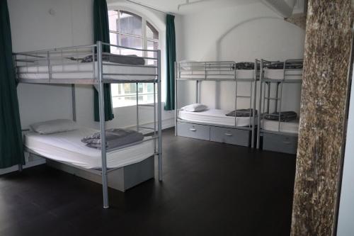 a room with three bunk beds and a window at Nomads Sydney in Sydney