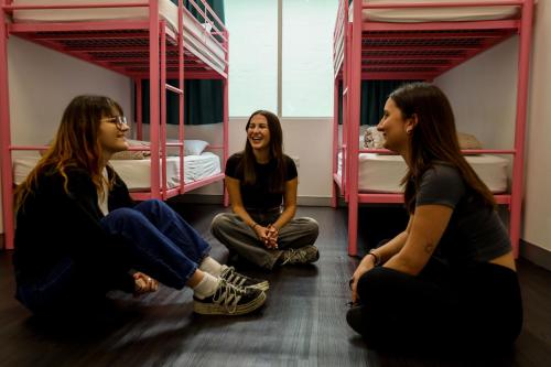 three girls sitting on the floor in a room with bunk beds at Nomads Sydney in Sydney