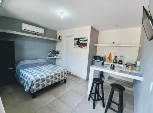 a bedroom with a bed and a desk with stools at Departamentos Caracoles Miramar in Ciudad Madero