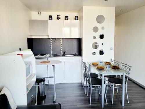 une cuisine avec des armoires blanches et une table et des chaises dans l'établissement Studio Cabine Moderne RDC, Terrasse, Parking, Proche Mer, 500m Plage, 4 Pers, Animaux OK - FR-1-794-140, à Canet