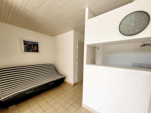 une chambre avec un lit et une horloge au mur dans l'établissement Studio cabine avec terrasse, accès direct plage, WIFI, clim, parking privé - 4 pers. - FR-1-794-149, à Canet