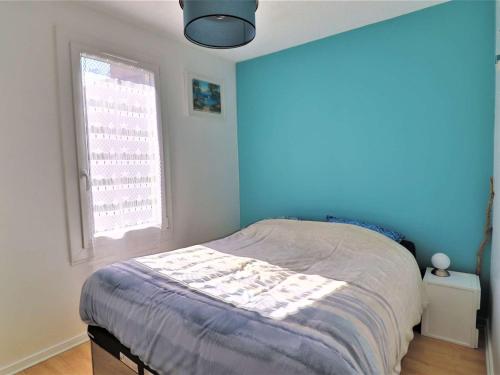 une chambre avec un lit avec un mur bleu dans l'établissement Charmant appartement avec jardin, proche plages, commerces et Royan, parking privé - FR-1-494-195, à Saint-Georges-de-Didonne