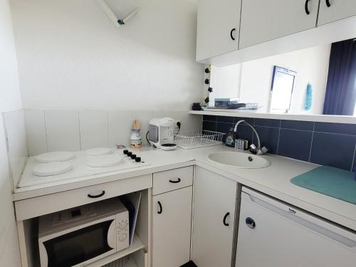 une petite cuisine avec un évier et un micro-ondes dans l'établissement Canet-en-Roussillon - Studio cabine 4/5 pers - bord de mer avec parking - FR-1-794-144, à Canet
