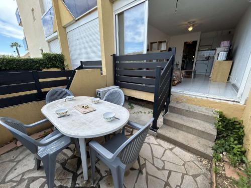 une table et des chaises assises à l'extérieur d'une maison dans l'établissement Studio cabine confortable, terrasse, proche plage et commerces - Le Grau du Roi - FR-1-250-284, au Grau-du-Roi