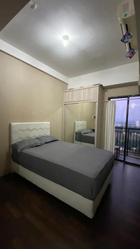 a bedroom with a bed and a large window at Apartemen Panoramic by Dio Property in Bandung