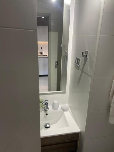 uma casa de banho branca com um lavatório e um espelho em Apartamentos Bauerle Curitiba em Temuco