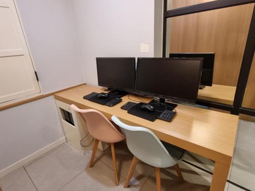 a desk with two computer monitors and two chairs at Jamsil Funny Hotel in Seoul