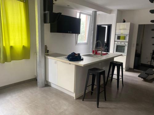 a kitchen with a counter and two bar stools at les lichens Tarbes in Tarbes