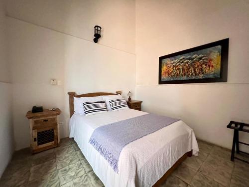 a bedroom with a bed and a painting on the wall at Hotel Boutique San Antonio in Cali
