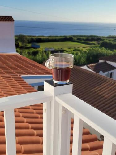 a cup of tea sitting on top of a white railing at Oceanview Sunset Retreat in Pilar