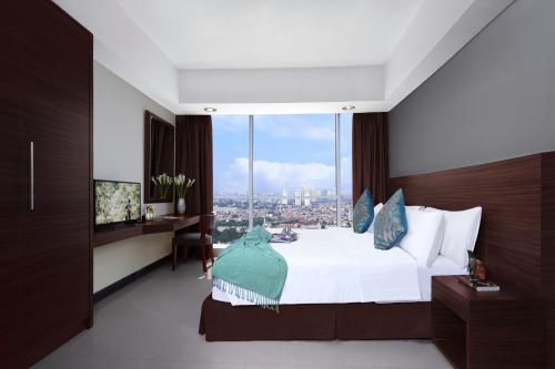 a bedroom with a bed with a view of a city at Somerset Kencana Jakarta in Jakarta
