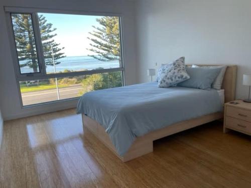 a bedroom with a bed and a large window at 4A Franklin Pde Encounter Bay - BYO Linen in Victor Harbor