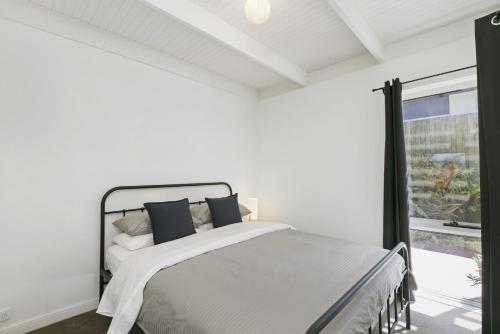 a white bedroom with a bed and a window at Mysa Anglesea Sleeps 7 WiFi SmartTV Cafes Shops in Anglesea