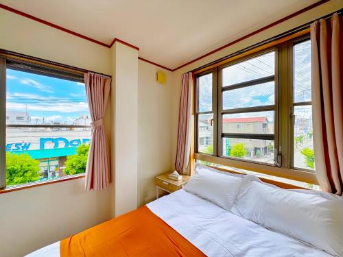 ein Schlafzimmer mit einem Bett und zwei Fenstern in der Unterkunft 大阪民泊ー和の家 in Osaka