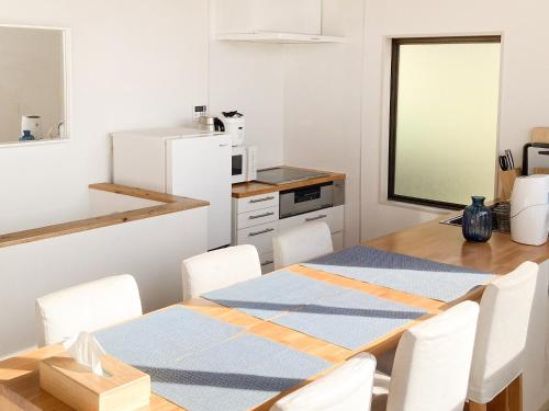 a kitchen with a table and chairs and a white refrigerator at and SEA The Terrace 海を感じながら料理を楽しみ開放的なTerraceで過ごす in Kamogawa