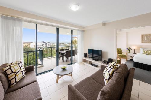 a living room with a couch and a bed and a television at Oaks Sunshine Coast Seaforth Resort in Alexandra Headland