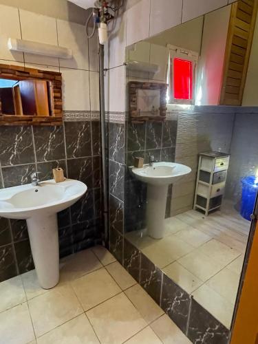 a bathroom with two sinks and a shower at Location Chambres chez Zam in Bandrélé