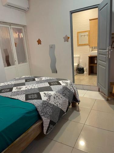 a bedroom with a bed with a black and white quilt at Location Chambres chez Zam in Bandrélé