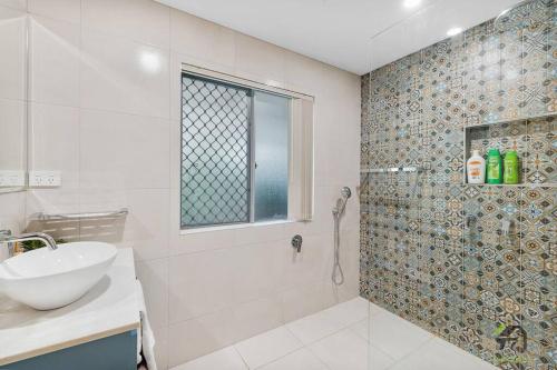 a white bathroom with a sink and a shower at Cozy Heaven Treeview House for Dream Trip in Springfield Lakes
