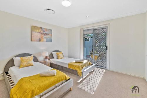 two beds in a room with a window at Cozy Heaven Treeview House for Dream Trip in Springfield Lakes