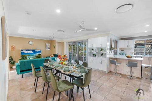 a dining room and living room with a table and chairs at Cozy Heaven Treeview House for Dream Trip in Springfield Lakes